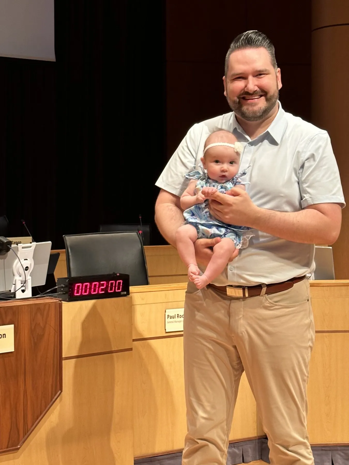Callan Morrison in council chambers holding one of Port Moody's youngest residents.